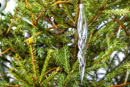 glass icicle on natural christmas tree close-up photo