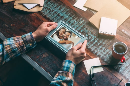 Good memories. Close-up top view image of man holding picture frame while sitting at the rustic wooden table photo