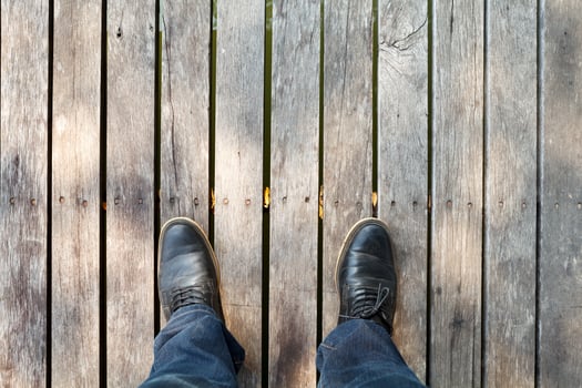 two legs wearing moccasins  and denim jeans on wooden background photo