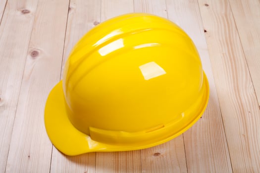 yellow hardhat architect on brown wood background photo