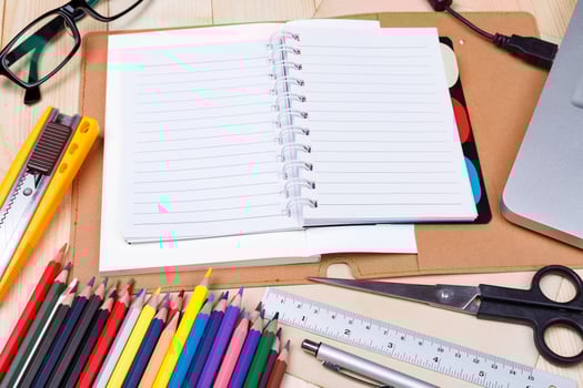 Workplace with colored pencils and supplies, laptop, notebook, eyeglass on wooden table photo