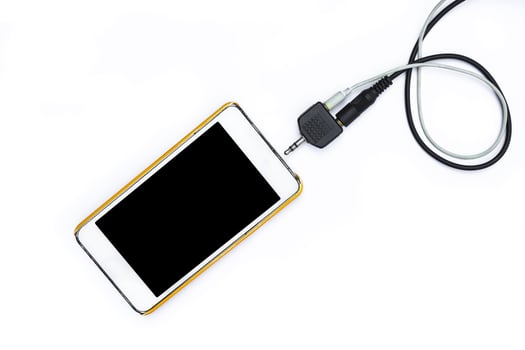 Smartphone with black and white jack plug on background photo