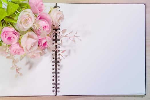 open note book with pink rose flowers on wooden background photo