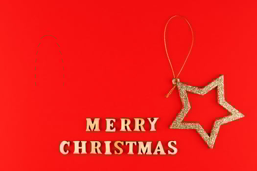 Festive greeting card. Merry christmas lettering on red background with golden glittering star. photo