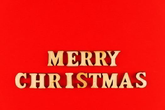 wooden letters on red background. Merry christmas lettering in red paper. Copy space photo
