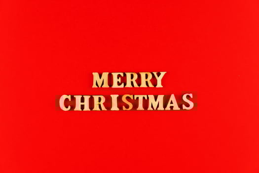 wooden letters on red background. Merry christmas lettering in red paper. Copy space photo