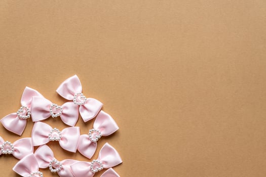 Pink satin bows with pearl hearts pattern on beige background. Festive concept for St Valentine's Day photo