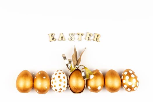 Easter festive decoration. Top view of easter eggs colored with golden paint and inscription in English Happy Easter. Wooden letters on white background. Various dotted design photo