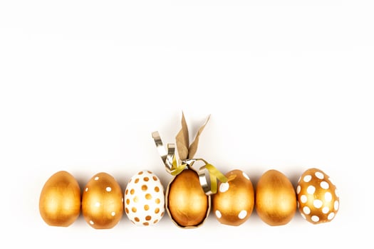 Easter festive decoration.Top view of easter eggs colored with golden paint on white background. Various dotted designs photo