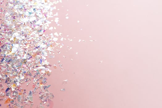 neon pearl foil confetti on light pink background. Festive, party or holiday glowing backdrop. Flat lay, top view. photo