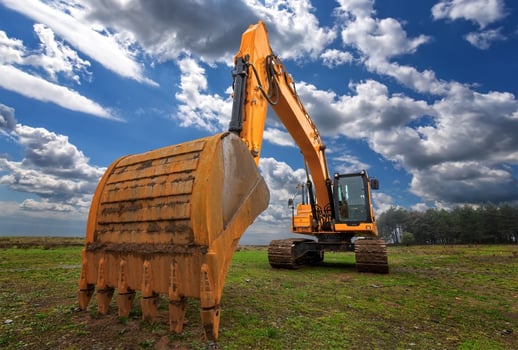 A stopped yellow excavator in a field and a beautiful sky photo