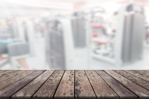 Empty wooden board space platform with blur fitness gym equipment background photo