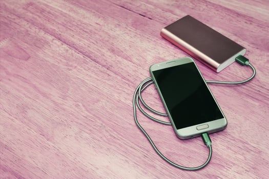 Smartphone charging with power bank on wood background,filter effect photo