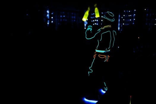 Professional barman and led light show. Silhouette of modern bartender shaking drink at night cocktail bar. photo