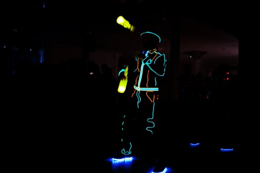 Professional barman and led light show. Silhouette of modern bartender shaking drink at night cocktail bar. photo