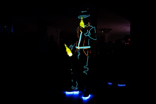 Professional barman and led light show. Silhouette of modern bartender shaking drink at night cocktail bar. photo
