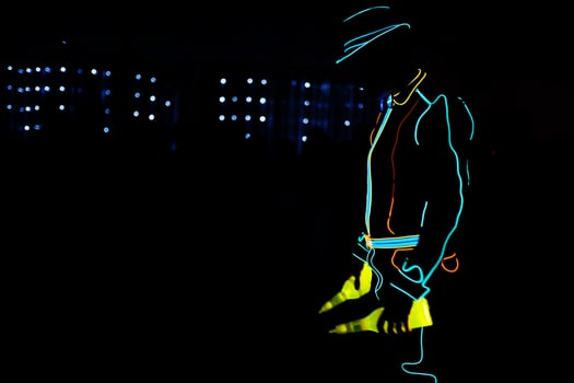 Professional barman and led light show. Silhouette of modern bartender shaking drink at night cocktail bar. photo