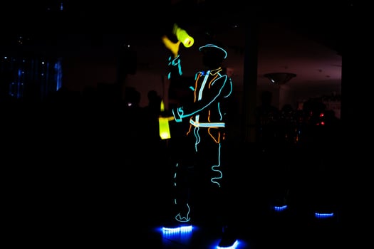 Professional barman and led light show. Silhouette of modern bartender shaking drink at night cocktail bar. photo