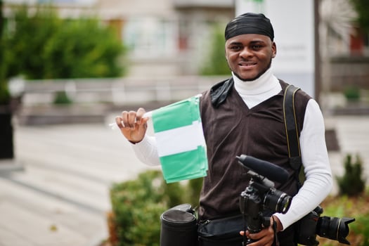 Young professional african american videographer holding professional camera with nigerian flags in hands. photo