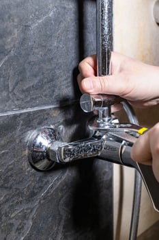 plumber repairing old shower faucet on tiled wall photo