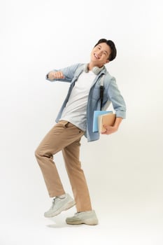 Portrait of smiling young college student with books and backpack against white background photo
