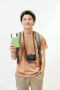Young man with suitcase, camera and ticket on white background photo
