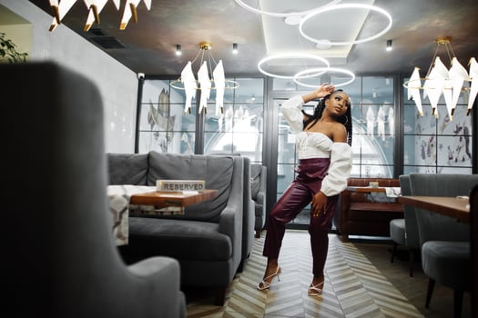Beautiful african american woman in white blouse and red leather pants pose at restaurant. photo