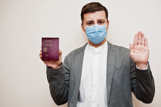 European man in formal wear and face mask, show Belgium passport with stop sign hand. Coronavirus lockdown in Europe country concept. photo