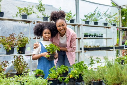 Portrait of African mother and daughter is choosing parsley from vegetable and herb plant section in the local garden center nursery for weekend gardening and outdoor concept photo