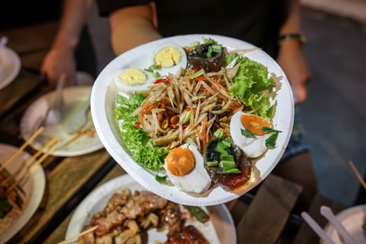 Somtum Spicy papaya salad with pickled fish in paper dish at foodtruck street food event., Bangkok, Thailand. photo