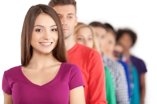 Standing in a row. Young people standing in a row while beautiful young woman standing in front of them and smiling photo