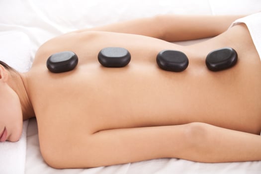 Stone treatment. Top view of beautiful young woman lying on front with spa stones on her back photo