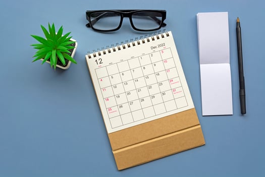 December 2022 desk calendar with notepad on blue background. Copy space. photo