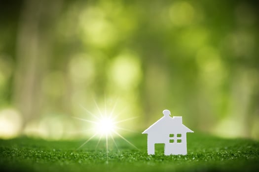 Environmentally eco-friendly real estate house. Small model building property home on grass in green nature ecology. Sustainable energy conservation residential design and sell - rent business concept photo