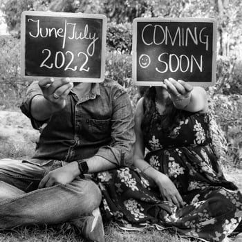 Indian couple posing for maternity baby shoot. The couple is posing in a lawn with green grass and the woman is falunting her baby bump in Lodhi Garden in New Delhi, India - Black and White photo