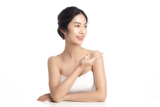 Asian woman with a beautiful face and Perfect clean fresh skin. Cute female model showing concept or idea on copy space on white isolated background. Facial treatment, Cosmetology, beauty Concept. photo