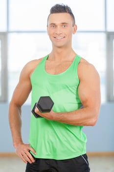 Fitness guy. Young handsome man in green shirt is lifting weights photo
