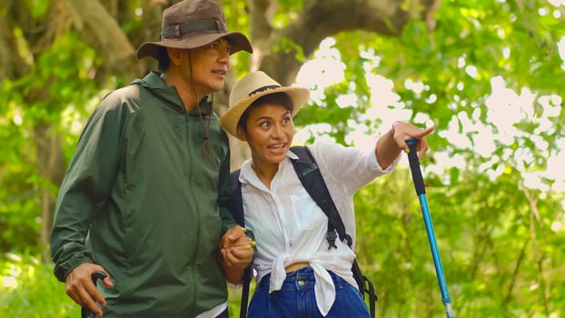 Asian mature couple enjoying nature trekking activities. Happy senior couple hiking with trekking sticks at the forest. photo