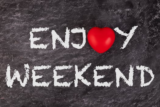 Enjoy weekend. The text is written on a school board with a white piece of chalk with a red heart. concept photo