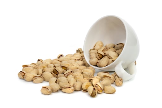 Closeup pistachios nut dry roasted and salted in a white coffee cup  isolated on white background photo
