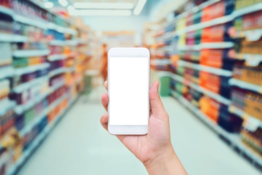 Female hand holding mobile phone with Supermarket background photo