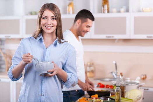 Cooking breakfast together. Happy couple cooking together in the kitchen while woman looking at camera and smiling photo