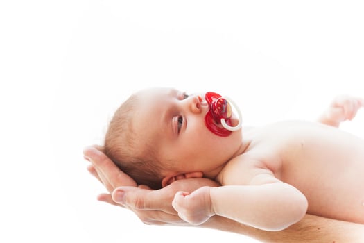 Little baby. Close-up of male hands holding cute little baby with pacifier in mouth photo