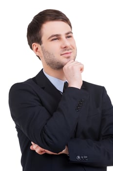 Business dreams. Cheerful young man in formalwear holding hand on chin and looking away while standing isolated on white photo