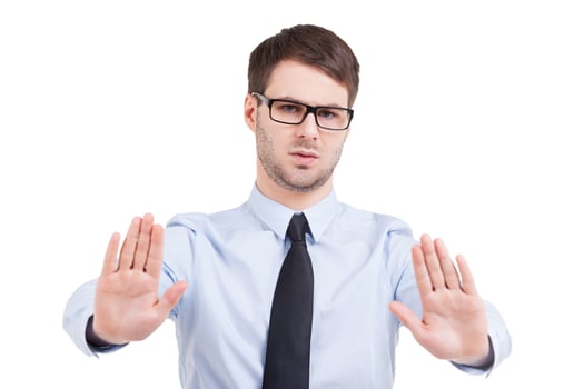 Stop it Serious young man in shirt and tie holding his hands outstretched while isolated on white photo