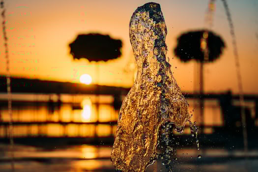stream of a fountain splashes water, sunset photo