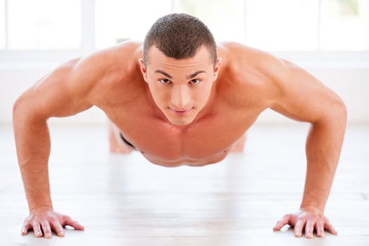 Man doing push-ups. Young muscular man doing push-ups and looking at camera photo