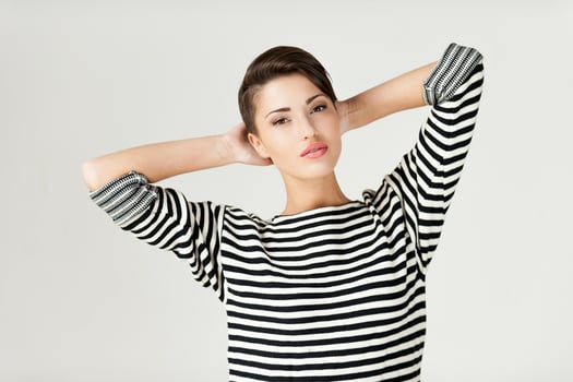 Hip and striped. Fashionable young short hair woman in striped clothing keeping arms crossed and looking at camera photo