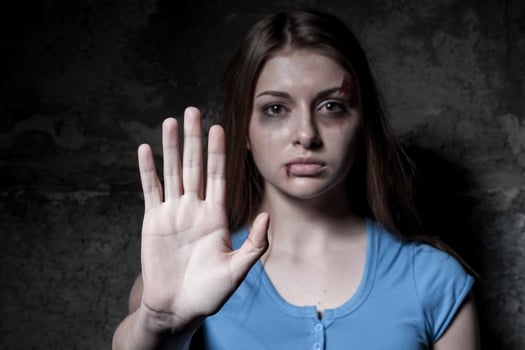 Stop hurting woman Young beaten up woman looking at camera and stretching out hand while standing against dark wall photo