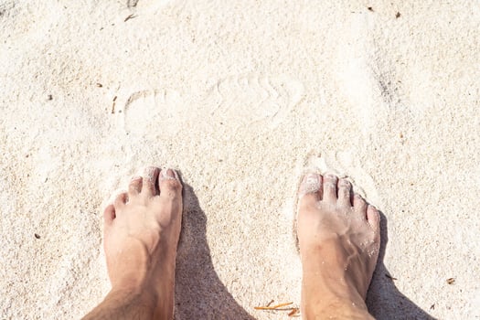 2 feet on the bleach. Close up of young man feet on a tropical sandy beach. photo